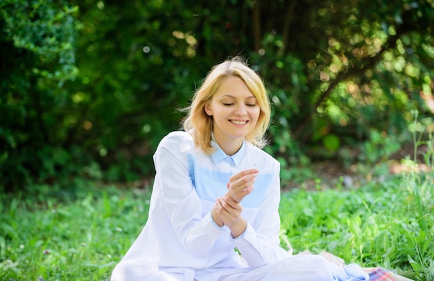 A mulher gosta de relaxar o fundo da natureza a senhora gosta de fragrância de flor tenra feminilidade e ternura menina loira tenra cheira uma flor minúscula enquanto se senta no prado de grama verde conceito puro e macio