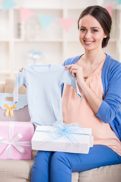 A mulher gravida está sentando-se com presentes em um chuveiro de bebê.