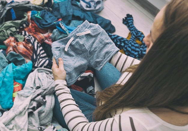 A mulher grávida está separando as roupas do bebê