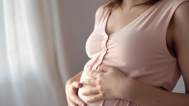 A mulher grávida no vestido segura as mãos na barriga em um fundo branco Feche o corte da mulher grávida no vestido verde tocando acariciando a barriga esperando o primeiro bebê