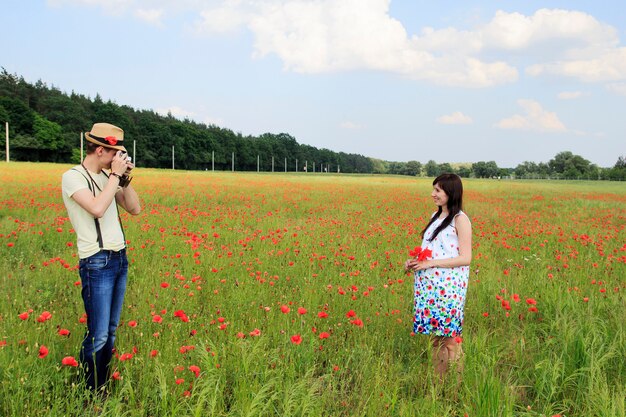 A mulher gravida nova adorável e o homem feliz fazem uma foto de sua esposa grávida.