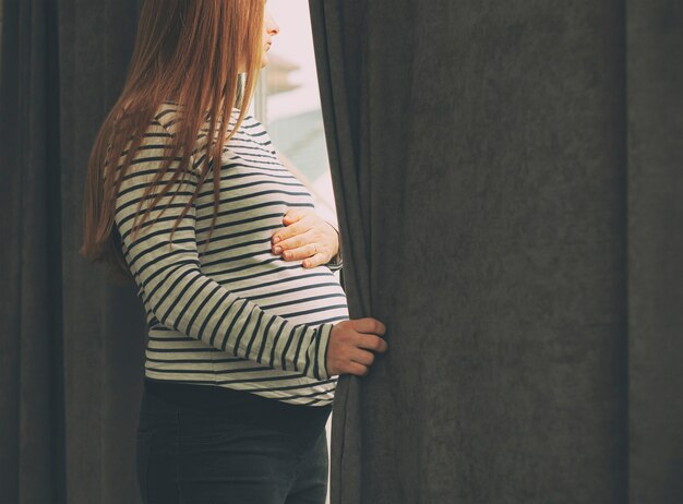 Foto a mulher grávida parada na janela