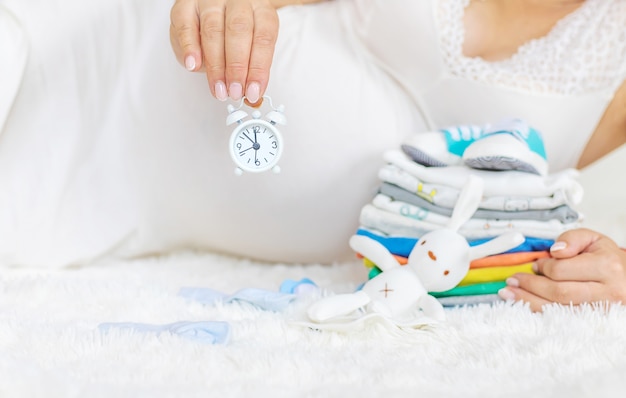 A mulher grávida tem um despertador nas mãos.