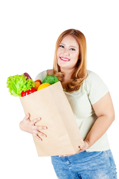 Foto a mulher guarda o saco de papel com vegetais no estúdio