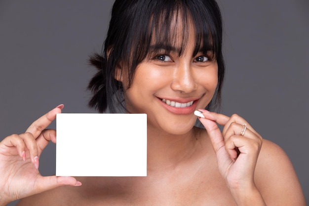 A mulher indiana asiática mostra um sorriso lindo, lábios felizes seguram uma caixa vazia em branco para tratamento de pele
