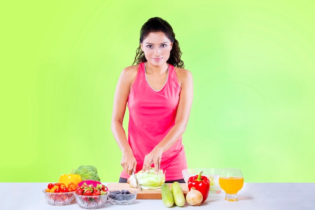 A mulher indiana cortou a alface para preparar a salada no estúdio