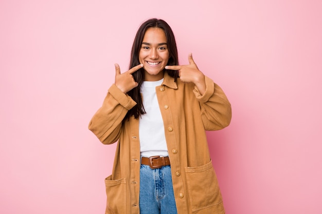 A mulher indiana nova da raça misturada isolou os sorrisos, apontando os dedos na boca.