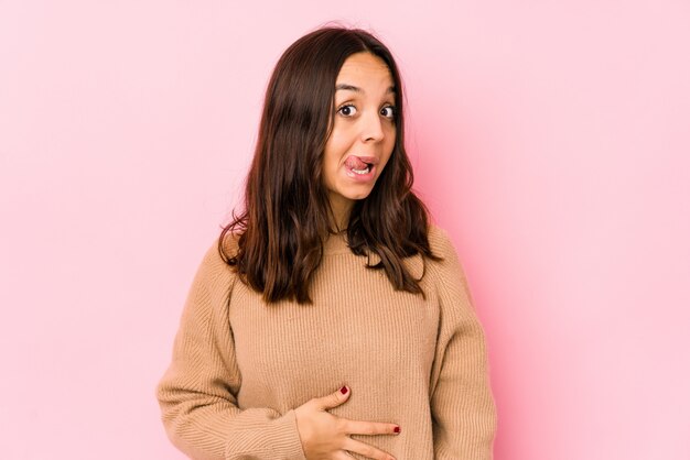 A mulher latino-americano nova da raça misturada isolada toca na barriga, sorri delicadamente, comendo e conceito da satisfação.