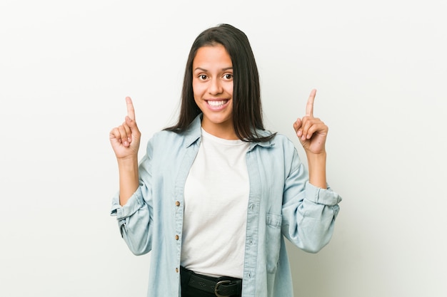 A mulher latino-americano nova indica com ambos os dedos dianteiros que mostram acima um espaço em branco.