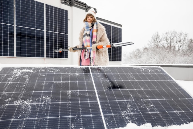 A mulher limpa os painéis solares da neve