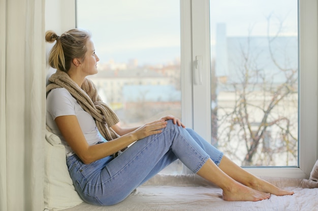 A mulher moderna está pensando no futuro, sentada no parapeito da janela. Conceito de liberdade pessoal