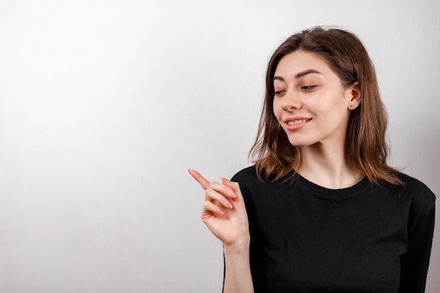 A mulher moreno nova de sorriso mostra o dedo ao lado no copyspase branco