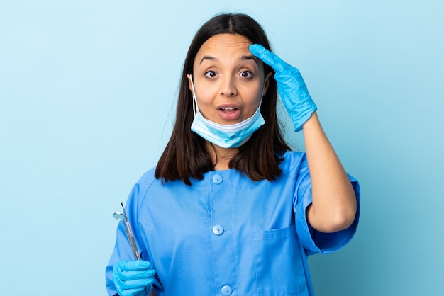 A mulher moreno nova do dentista da raça misturada que guarda ferramentas sobre isolado realizou algo