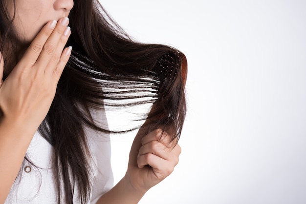 A mulher mostra sua escova com cabelo danificado da perda longa