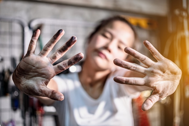 Foto a mulher mostra suas mãos sujas após o trabalho na garagem