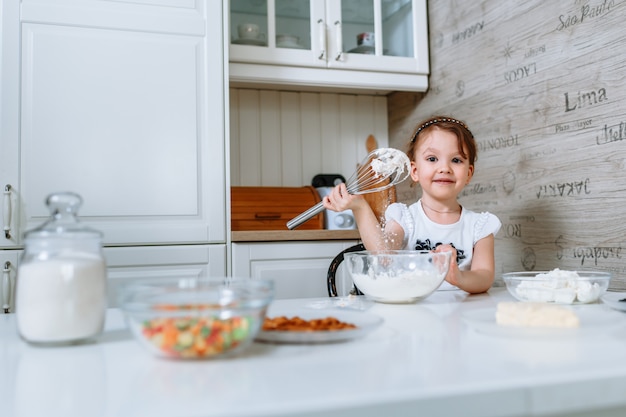 A mulher na cozinha bate a massa com um batedor de bolo