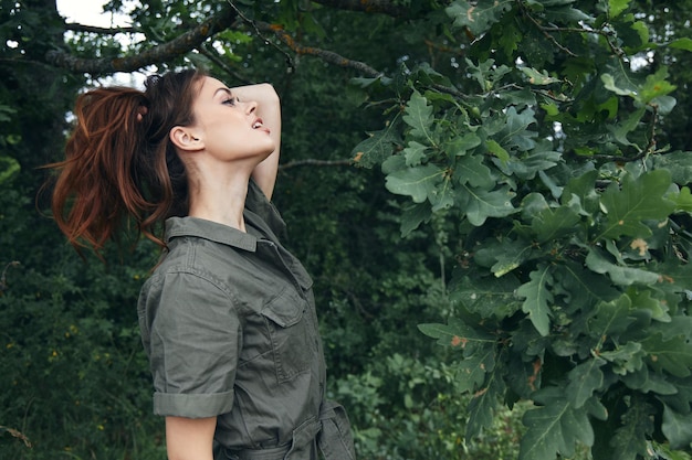 A mulher na floresta Mantém o cabelo nas mãos procura o ar fresco da natureza