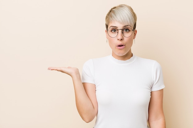 A mulher natural autêntica nova que veste uma camisa branca imprimiu guardar o espaço da cópia na palma.