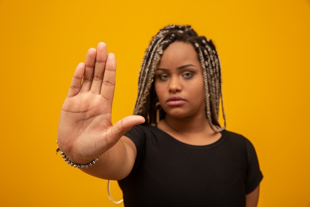 Foto a mulher nova do americano africano mostrou a mão no sinal para que parem com preconceito racial.