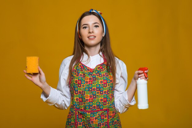 A mulher pinup segura uma mulher pinup de espanador de garrafa de sopa com cara feliz em fundo amarelo