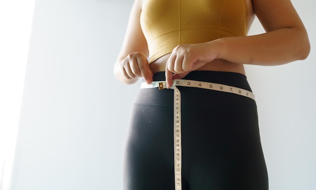 A mulher quer perder peso com um centímetro Forma muscular saudável do estômago e dieta medindo a cintura com fita métrica após o controle de peso da dieta