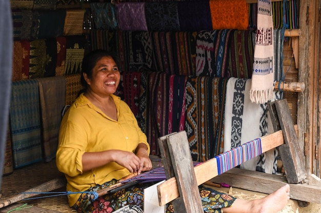 A mulher Sasak tradicionalmente faz fios com uma roda de fuso na aldeia tradicional de Sasak, Lombok