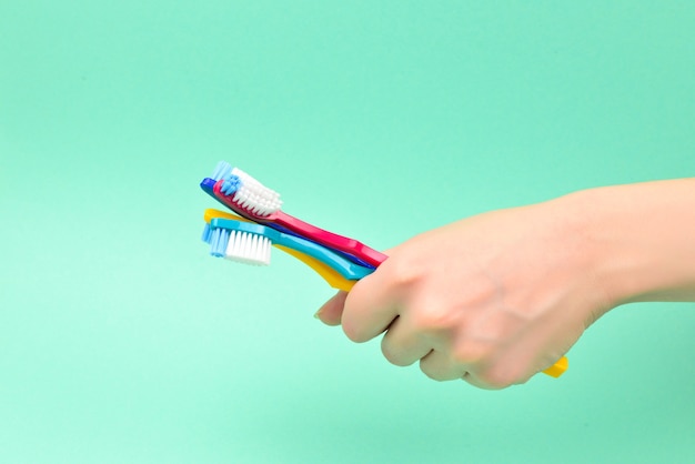 Foto a mulher segura as escovas de dente nas mãos sobre um fundo verde.