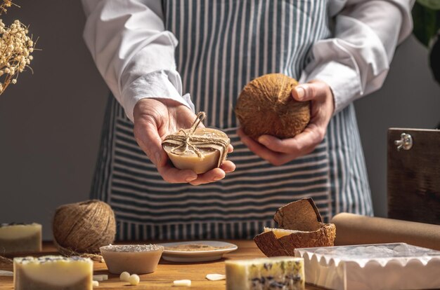 A mulher segura um pedaço de sabão natural e um coco em suas mãos Conceito de fazer cosméticos orgânicos um passatempo interessante eco presentes feitos à mão