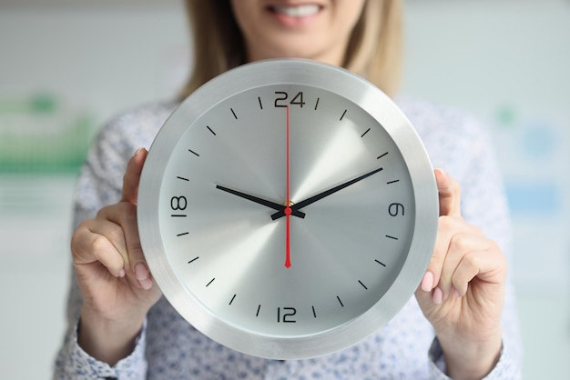 A mulher segura um relógio redondo na frente de seu corpo fechando o conceito de prazo de passagem do tempo e
