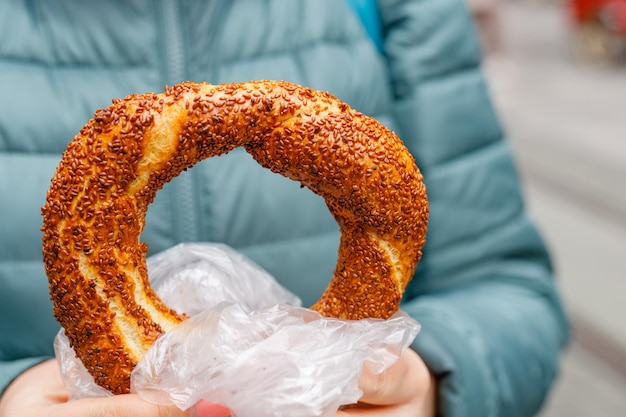 A mulher segura um simit turco tradicional nas mãos e quer comê-lo