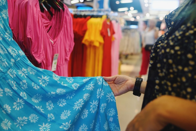 Foto a mulher seleciona um vestido da mulher em uma loja