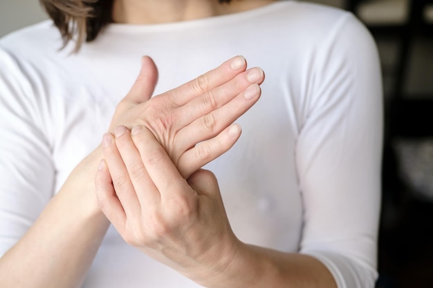 A mulher sente dor em seu braço e massageia sua palma dolorida