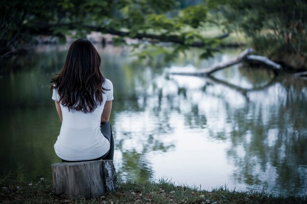 A mulher sentou-se tristemente perto do lago. a depressão tem um grande impacto nas relações familiares e interpessoais