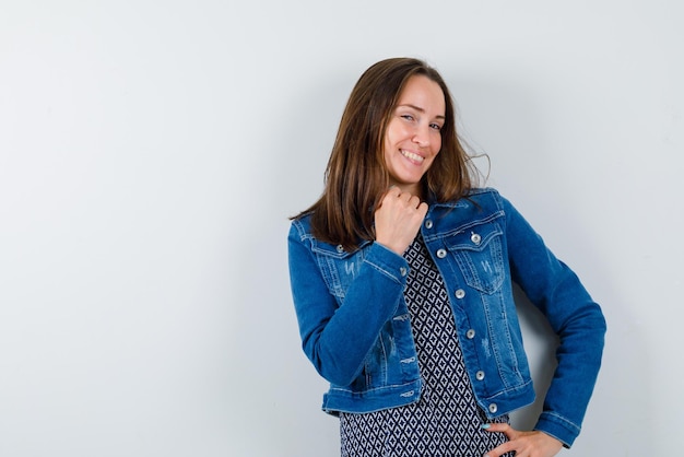 A mulher sorridente está segurando o punho sob o queixo no fundo branco