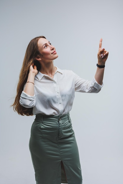 A mulher sorridente na camisa branca recomenda optar por anunciar o dedo indicador para o lado na maquete do espaço de cópia da área de promoção comercial do espaço de trabalho isolado no fundo branco