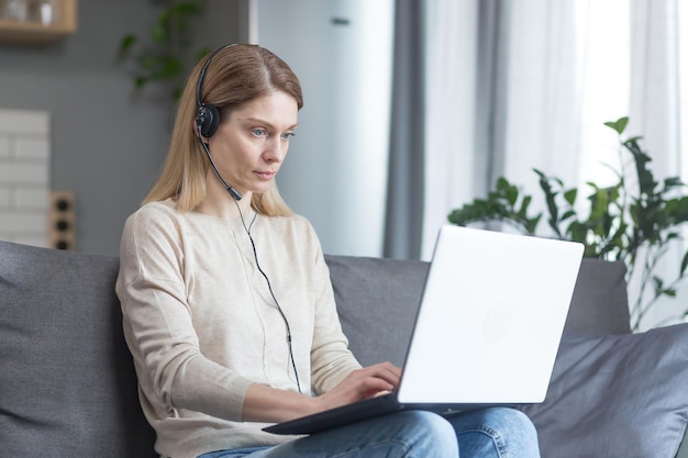 A mulher trabalha remotamente em casa como consultora online usa fone de ouvido e laptop para uma videochamada