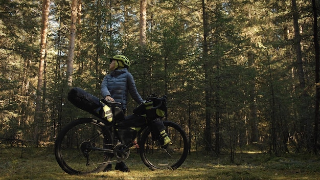 A mulher viaja em ciclismo de terreno misto com bike bikepacking A viagem do viajante com bolsas de bicicleta Magic forest park