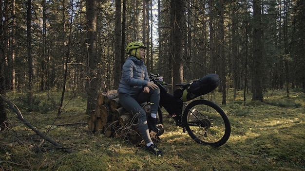 A mulher viaja em ciclismo de terreno misto com bike bikepacking A viagem do viajante com bolsas de bicicleta Magic forest park