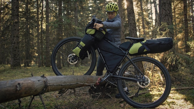 A mulher viaja em ciclismo de terreno misto com bike bikepacking. A viagem do viajante com malas de bicicleta. Parque da floresta mágica.