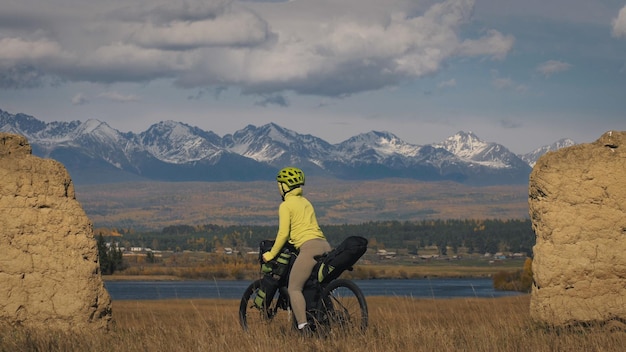 A mulher viaja em ciclismo de terreno misto com bikepacking a viagem do viajante com bolsas de bicicleta turismo esportivo bikepacking