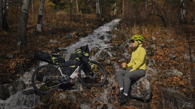 A mulher viaja em passeios de bicicleta de terreno misto com bikepacking viagem de viajante com bolsas de bicicleta