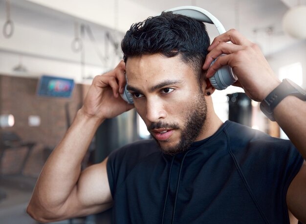 A música agora permite começar Foto de um jovem esportivo ouvindo música enquanto se exercita em uma academia