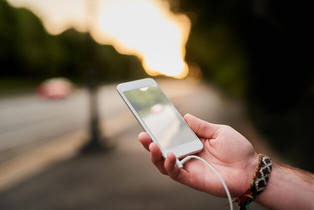 Foto a música é o melhor companheiro de viagem foto de alto ângulo de um homem irreconhecível ouvindo música em seu celular enquanto caminha pela cidade