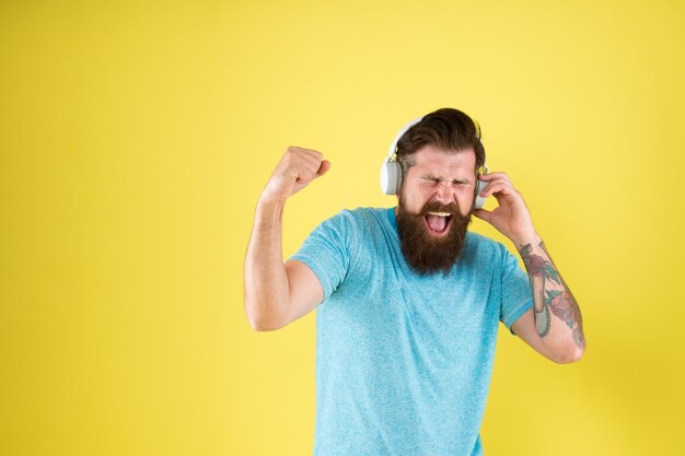 A música tem poder de cura Cantor de música emocional Hipster canta música tocando em fones de ouvido Homem barbudo faz vocal na música fundo amarelo A música me deixa mais forte Espaço para cópia