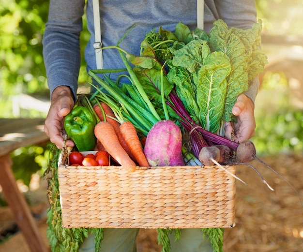 A natureza sabe melhor foto recortada de um homem carregando uma cesta de produtos recém-colhidos em um jardim