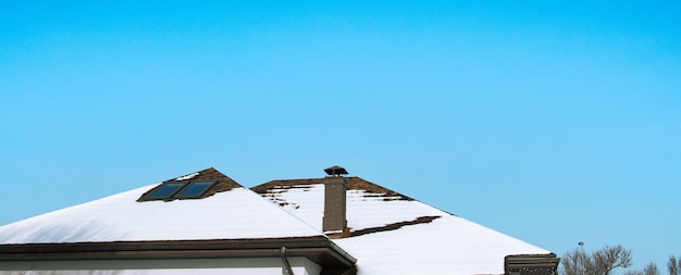 A neve derrete no telhado da casa sob os raios do sol de fevereiro