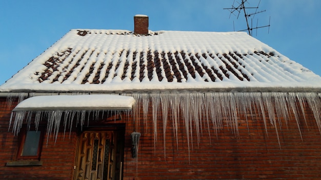 A neve derretendo para ser gelo no telhado da casa