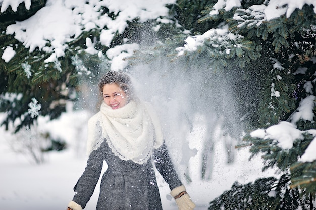 A neve do natal voa em uma menina no parque no inverno com árvores cobertas de neve