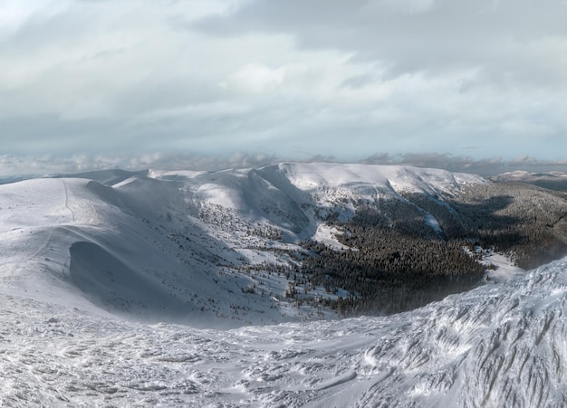 A neve e o vento formaram formações de gelo cobertas de inverno no topo do planalto com cornijas de neve em longe Magnífico dia ensolarado em uma pitoresca e bela cordilheira alpina