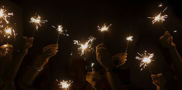 A noite escura celebra o conceito com muitas mãos pegando e usando luz brilha fogo juntos se divertem na véspera de ano novo ou festa companheirismo e amizade durante a celebração feliz estilo de vida